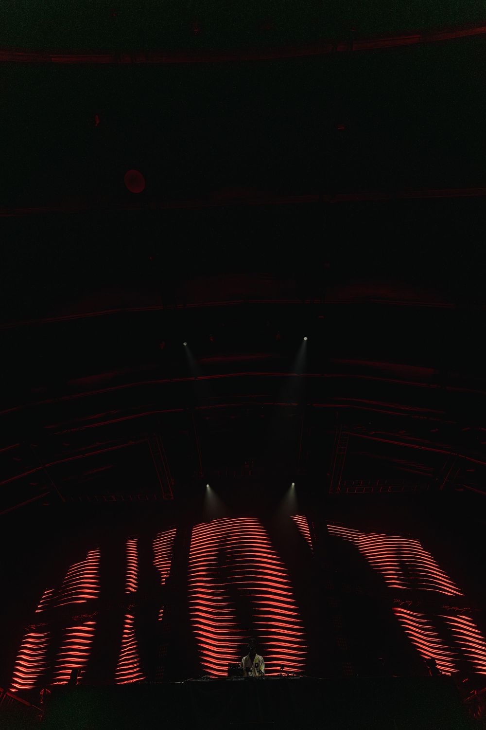 Red neon lights create a wavy pattern against a dark background in a modern architectural setting.