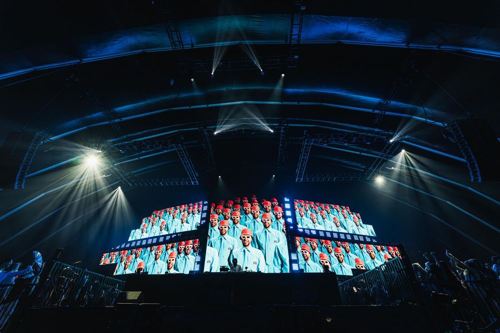 A panoramic sequence showing a large illuminated stadium or arena structure at night with dramatic lighting effects.