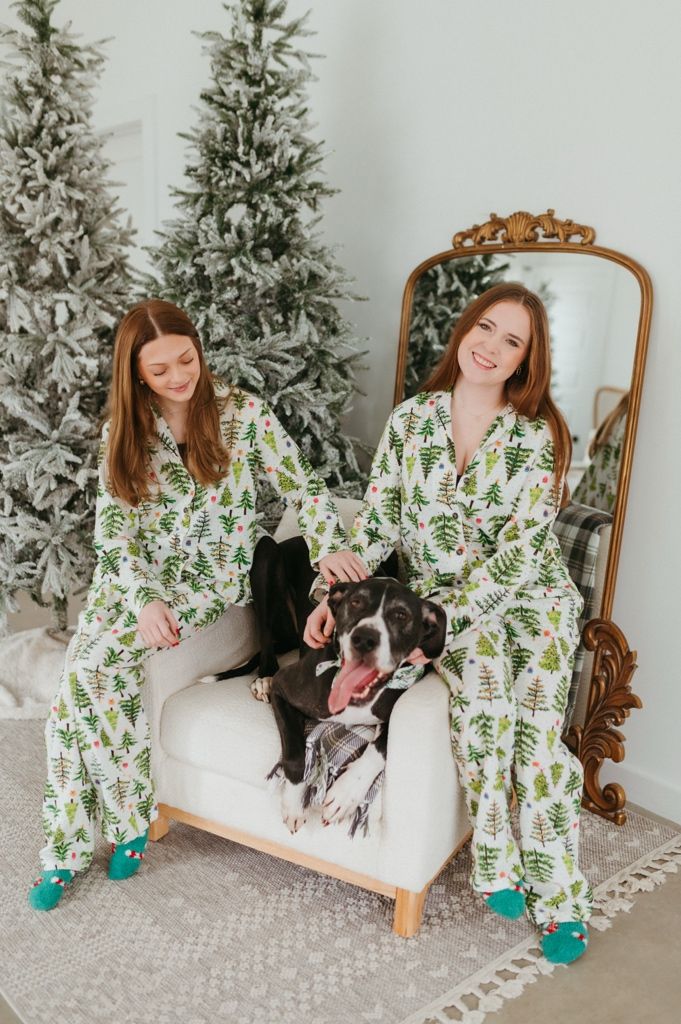 Festive holiday photoshoot with a Christmas tree and decorative chair in a bright white room.