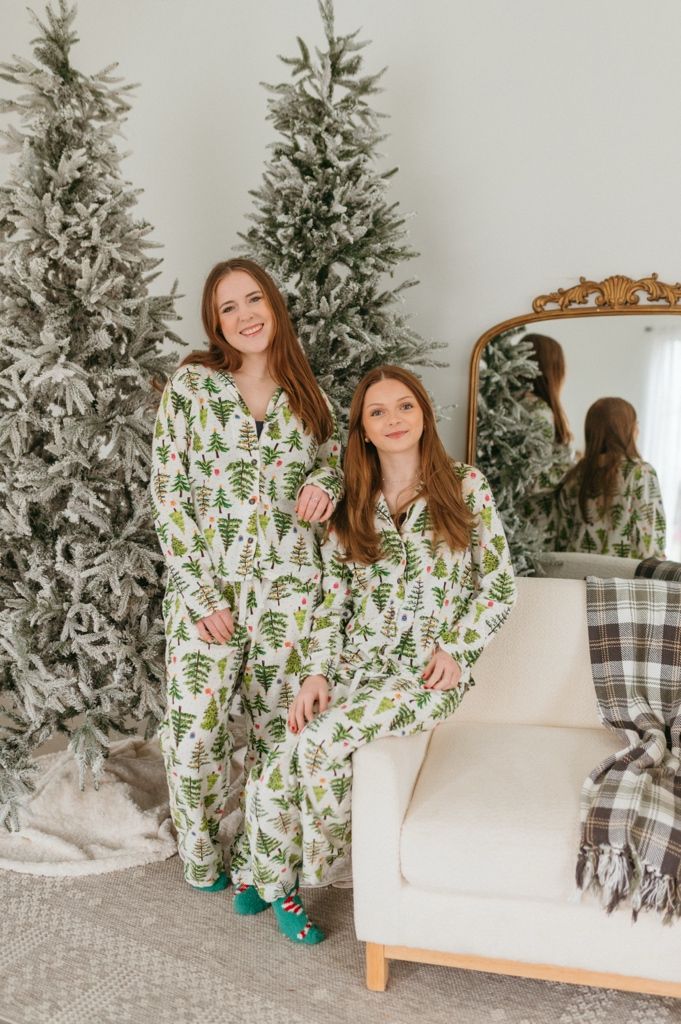 Holiday scene with matching green and white patterned pajamas against a decorated Christmas tree and cozy decor.