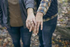 A person wearing a plaid flannel shirt and jeans holds a small object in their hands while standing outdoors.