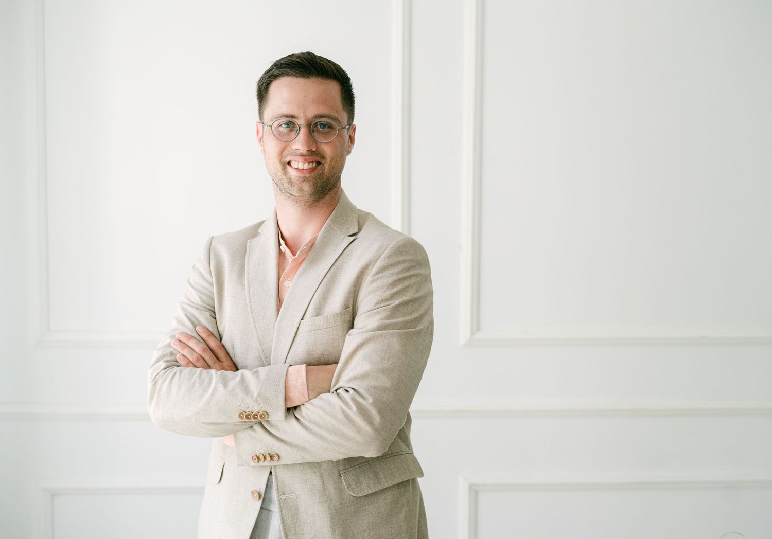 Professional in a crisp white shirt poses with crossed arms and confident smile against white background.