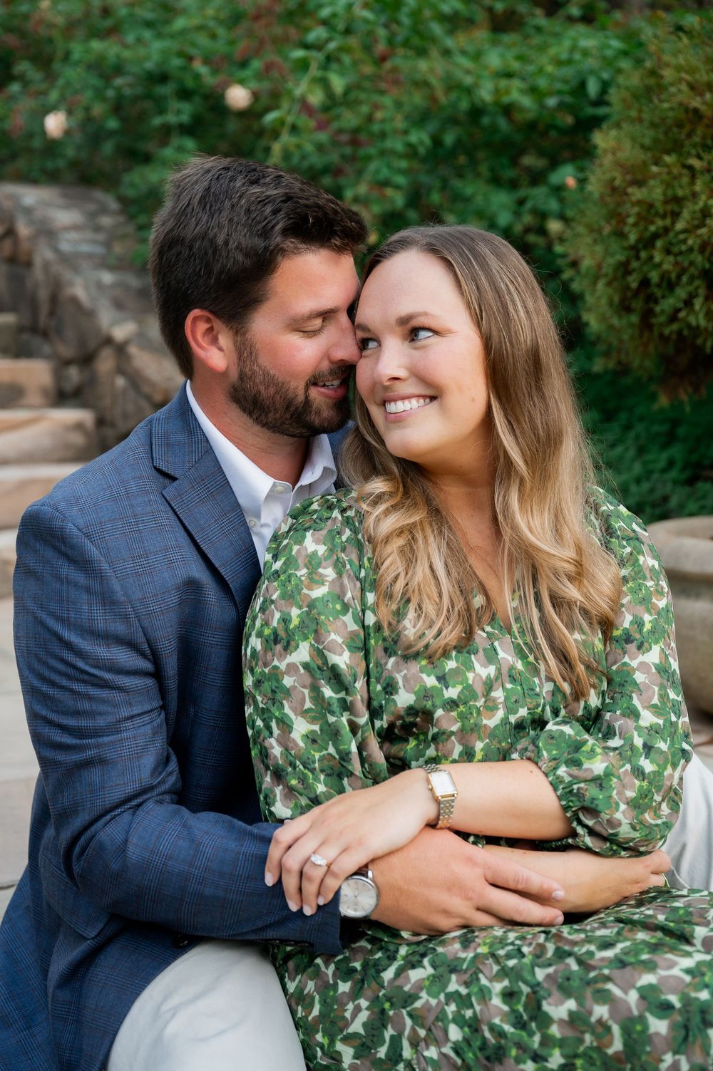 A couple sharing intimate moments while sitting together in a garden setting.