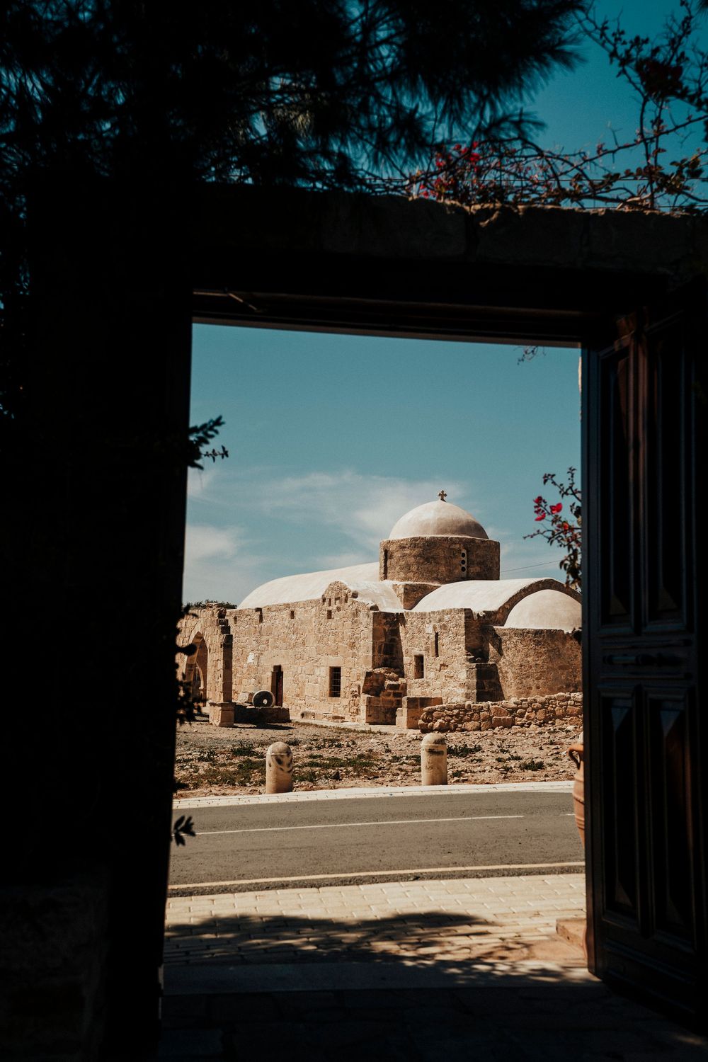 View through doorway of ancient stone buildings with domed roofs against blue sky in desert landscape.