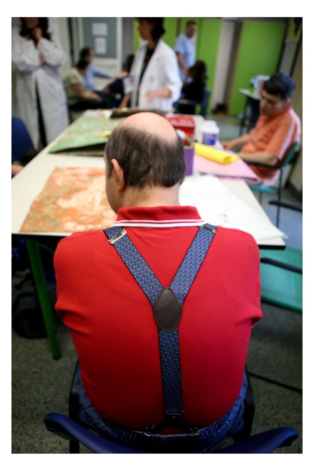 Close-up view of blue polka dot suspenders against a red shirt showing Y-shaped back pattern.