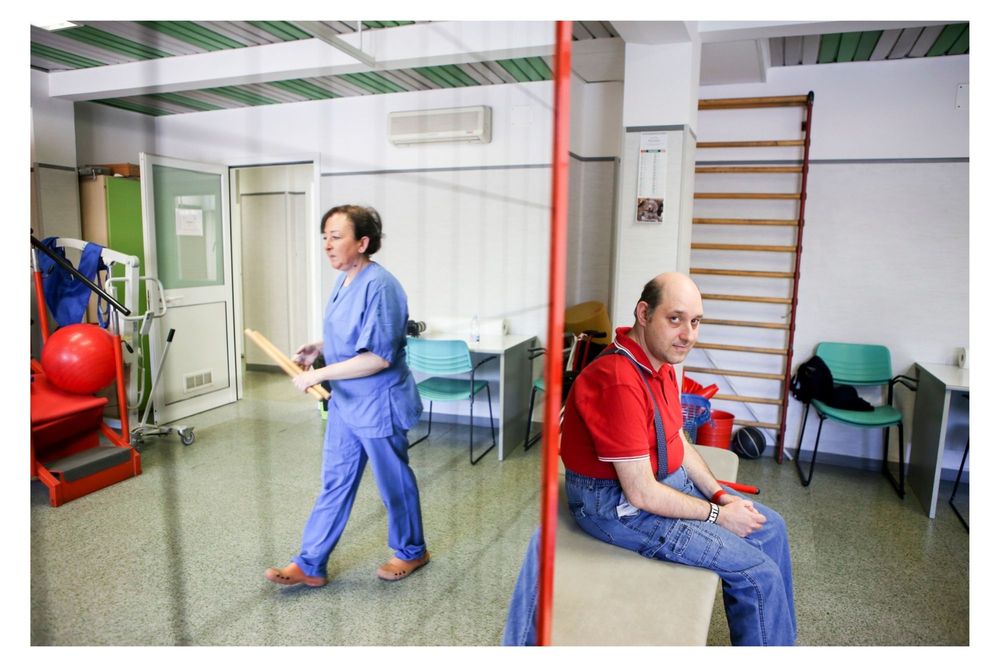Healthcare workers in blue scrubs clean and sanitize a medical facility hallway.