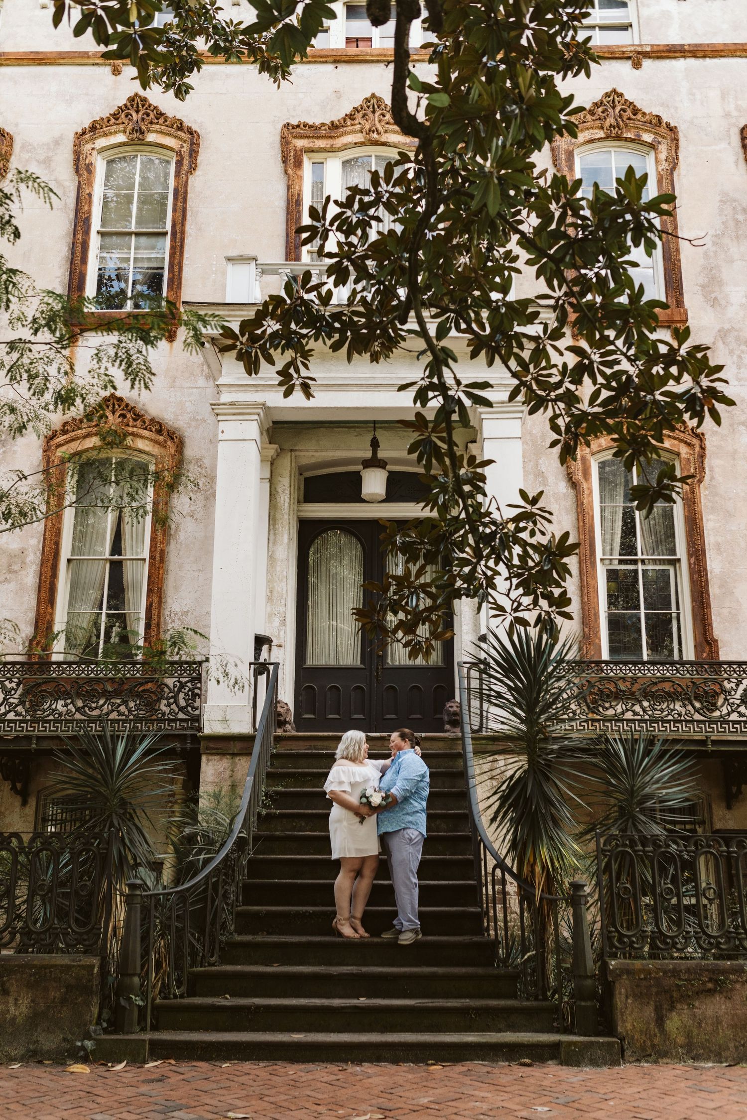 A series of romantic engagement photos taken on the steps of a historic building with ornate iron railings and greenery.