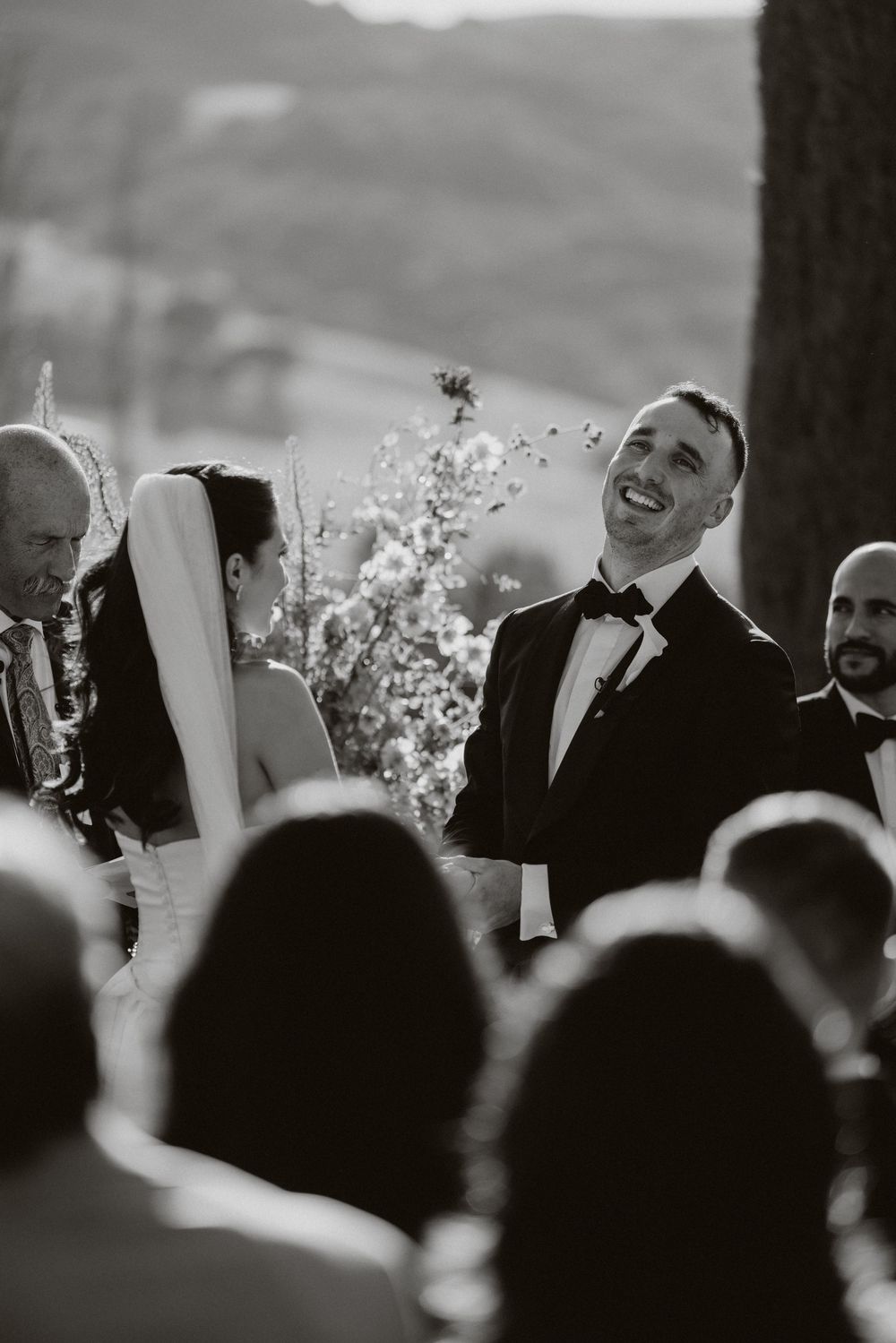 A black and white photo sequence showing joyful wedding celebration moments with guests raising glasses in celebration.