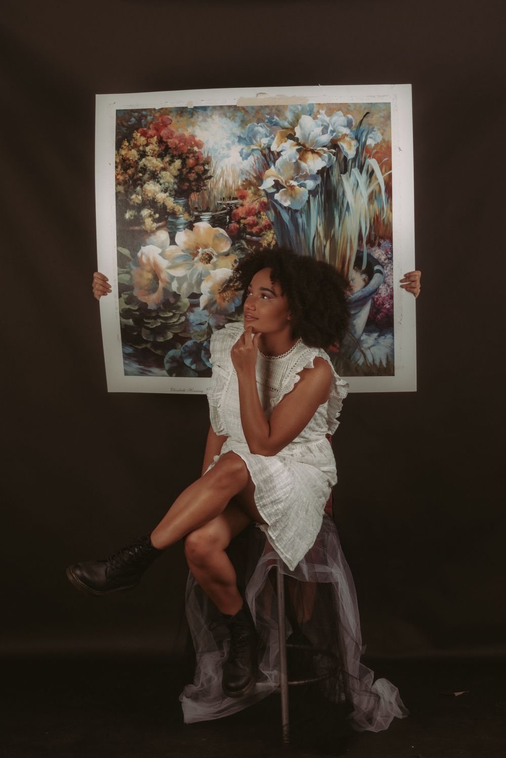 Studio portraits with white dress and decorative artwork backdrop in editorial moody lighting.