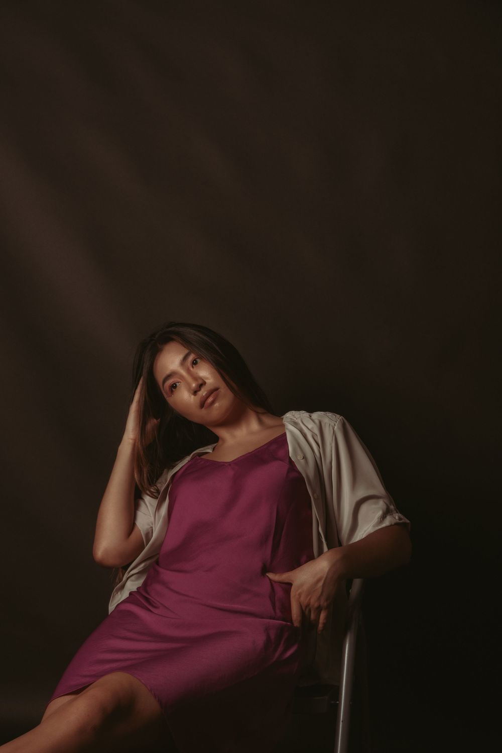 Dramatic editorial portrait series showing relaxed poses in purple top against dark background.