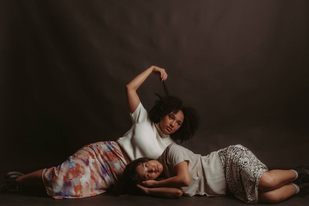 Artistic editorial photo series showing relaxed poses on floor in dark studio setting.
