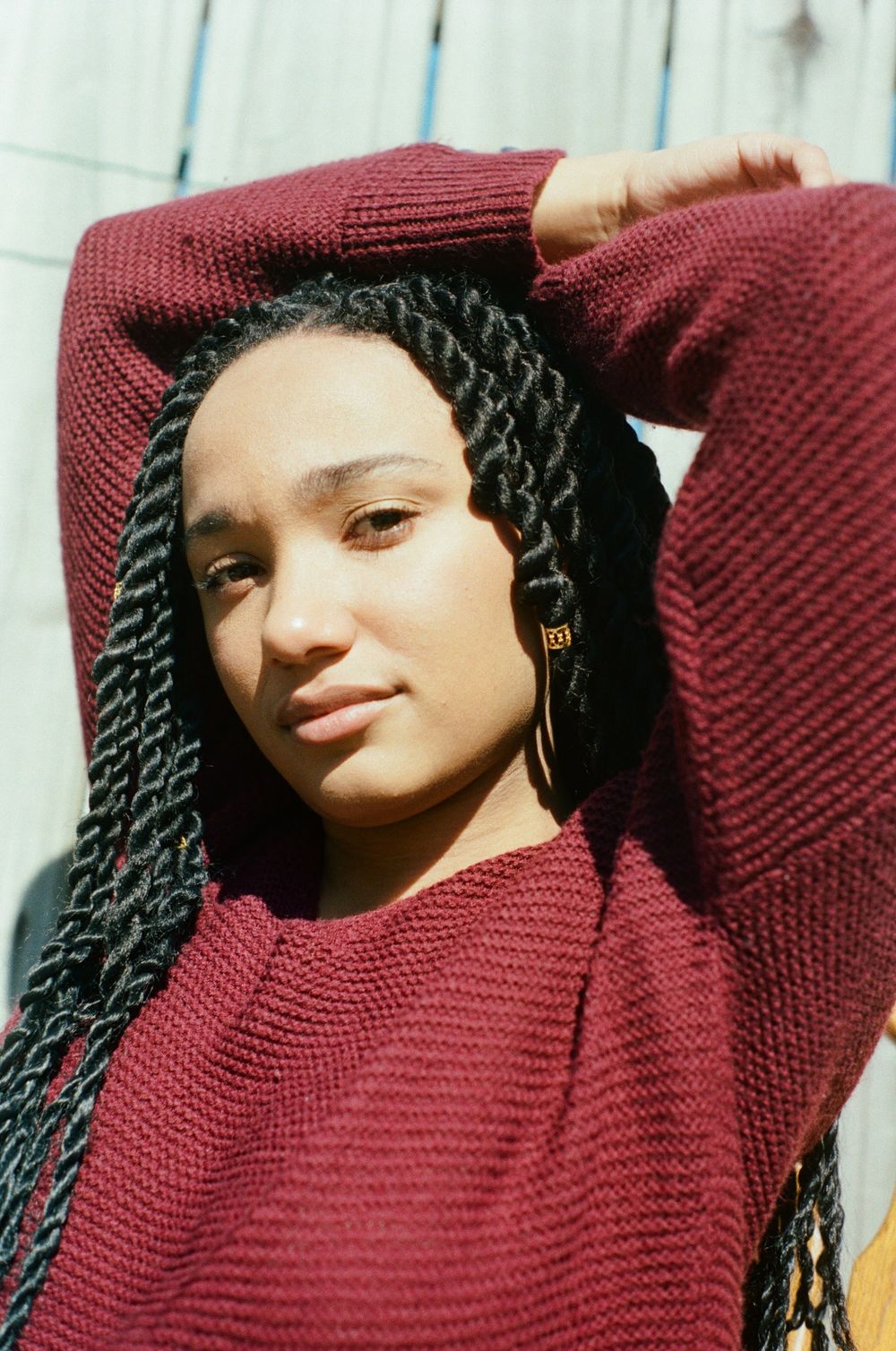 Close-up portrait series in burgundy sweater showing playful expressions in sunlight.