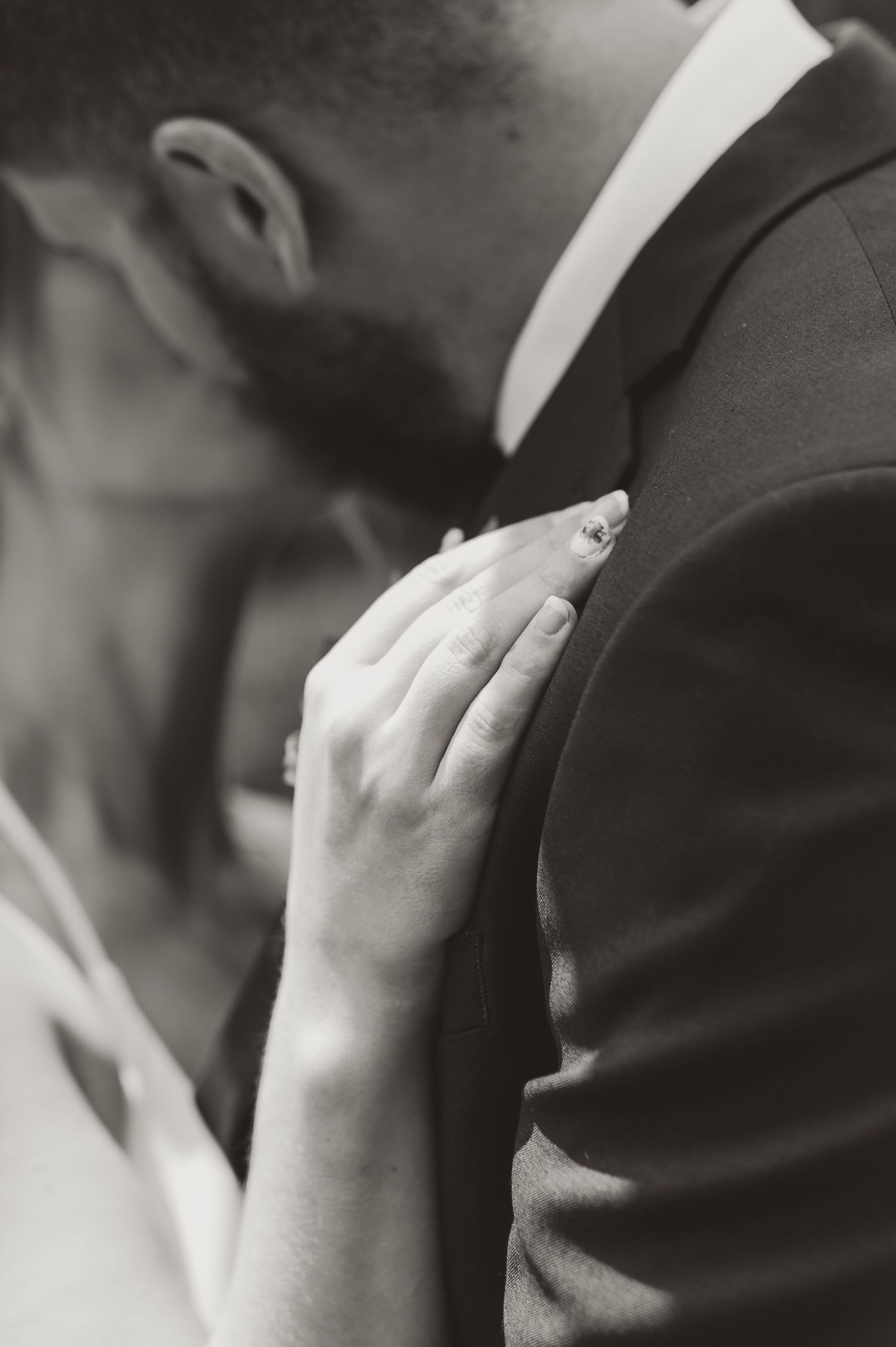Black and white wedding photo of bride resting hand on groom's chest in an intimate embrace.