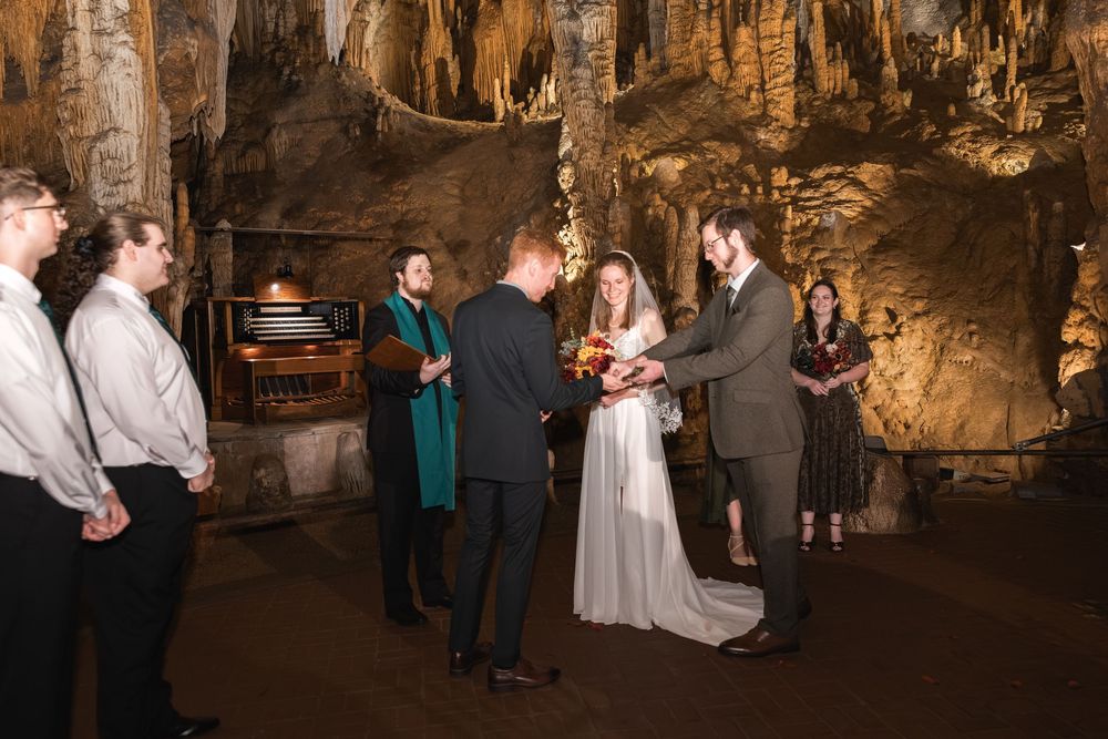 Wedding celebration in a natural cavern with dramatic rock formations and atmospheric lighting.