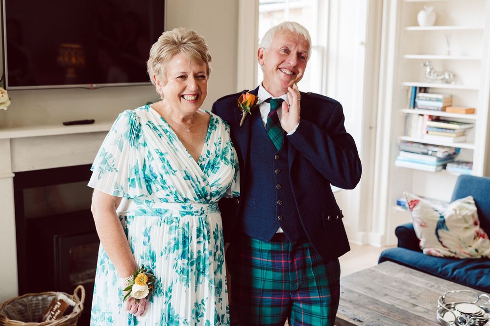 A couple in coordinating turquoise and navy outfits share a joyful moment while dancing together at home.