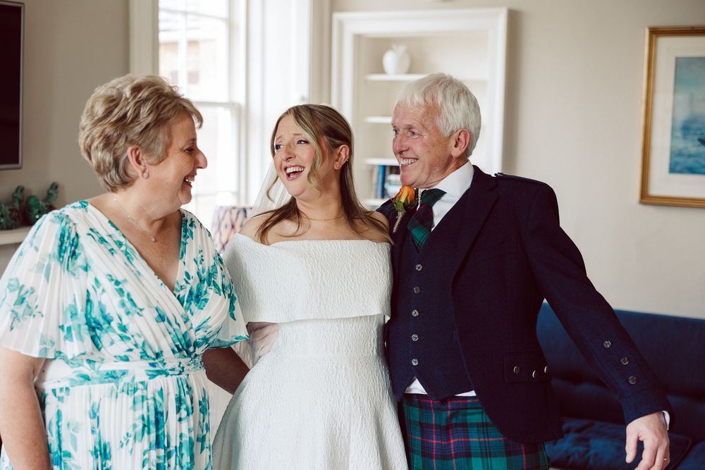 A group of people in formal attire gather at a wedding celebration, with turquoise accents and bright smiles.
