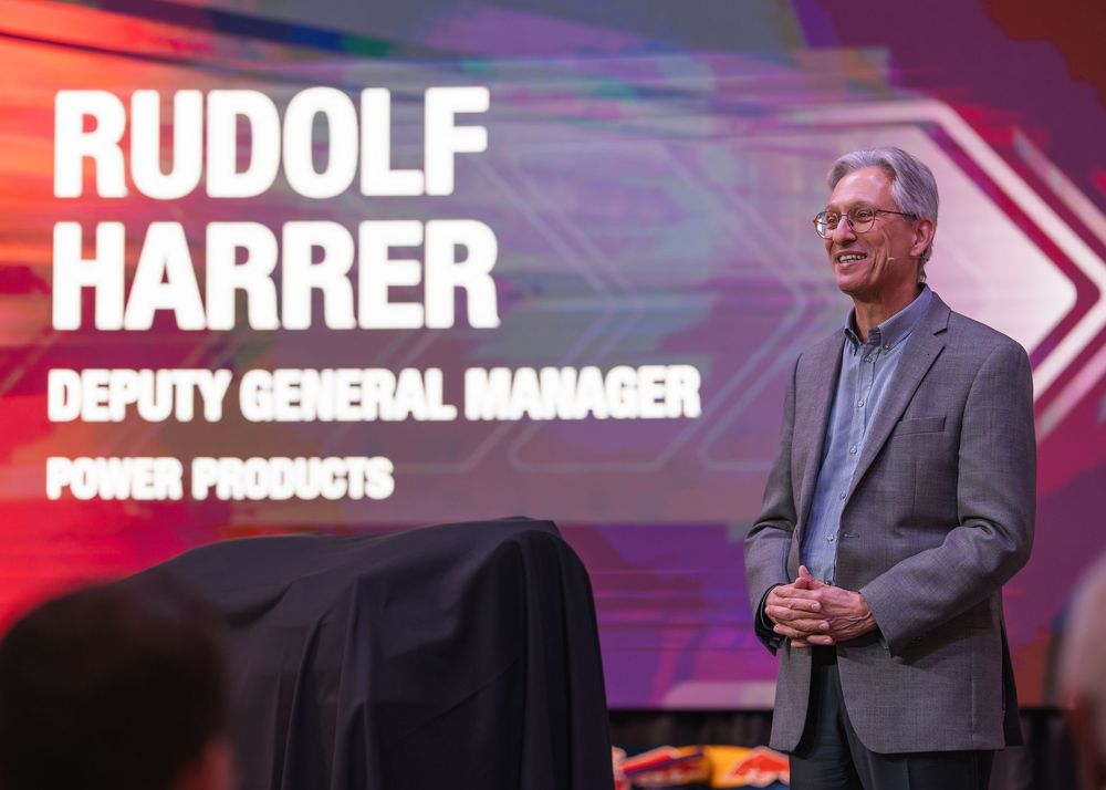 Corporate presentation stage with large digital display showing text and graphics.