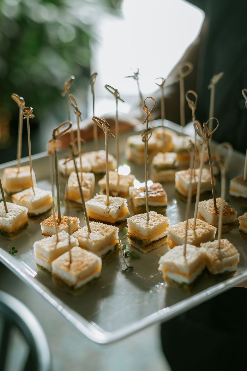 Gourmet appetizers on wooden picks displayed on silver platters at a wedding reception.