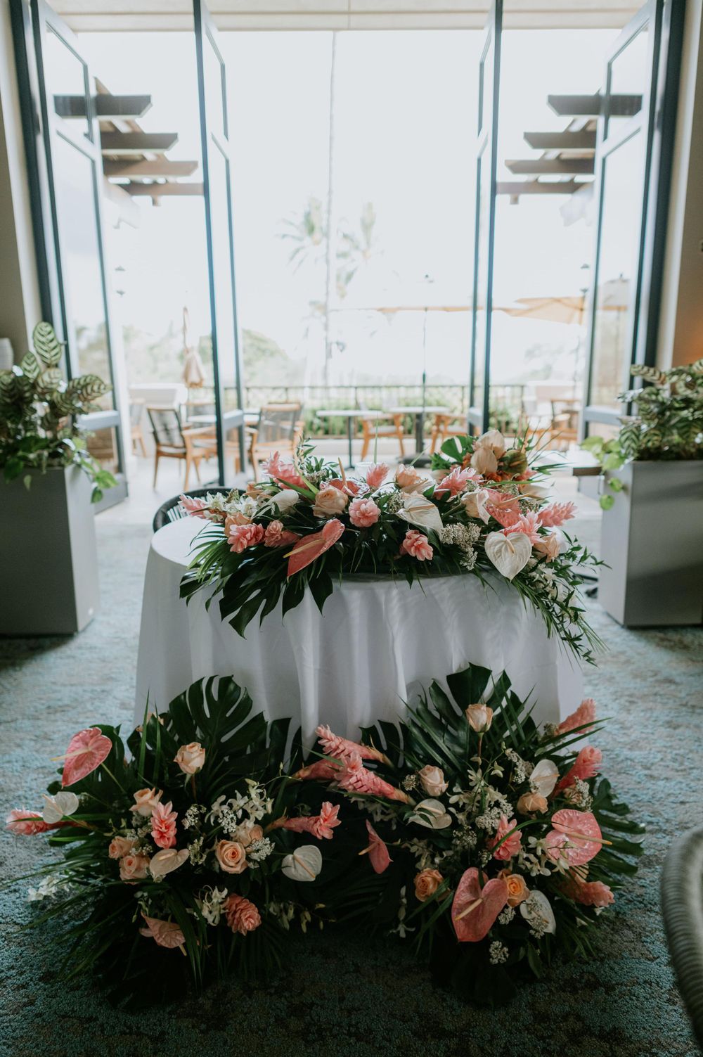 Luxurious floral arrangement with pink roses and greenery decorating a wedding venue.