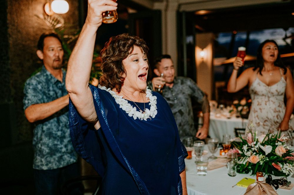 Wedding celebration with guests dancing and toasting in a modern indoor venue with decorative lighting.