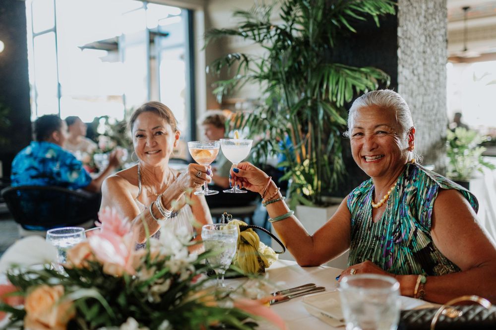 Wedding guests enjoying a celebration at an indoor tropical venue with natural lighting.
