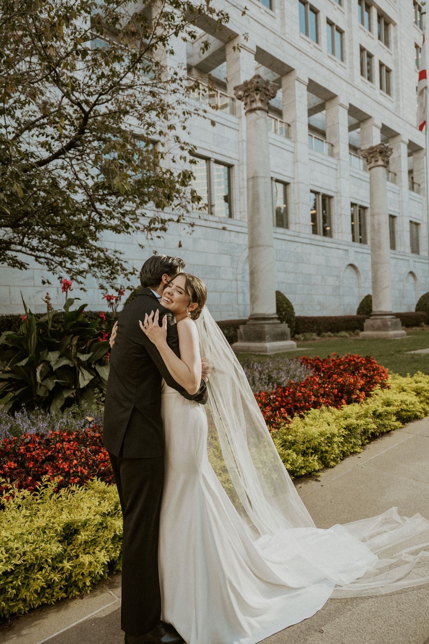 Beautiful wedding portrait in front of historic building with blooming garden.