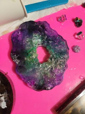 Crystal geode displays purple and green iridescent colors on pink surface.
