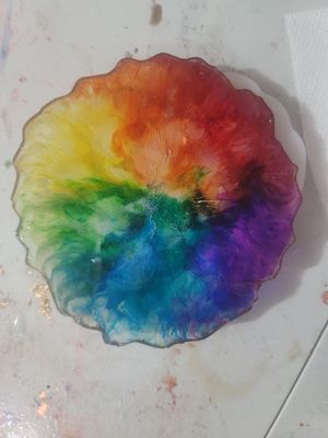 Circular watercolor painting featuring a vibrant rainbow color spectrum radiating from the center.