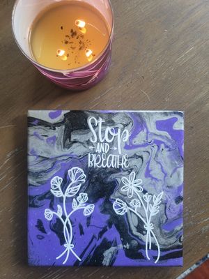 Purple and black marbled artwork with white text reading 'Stop and Breathe' next to a lit candle.