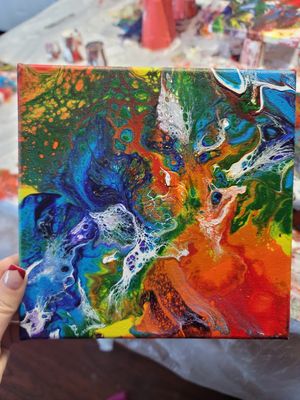 Vibrant pour painting with flowing colors of blue, orange, green and red creating dynamic patterns.