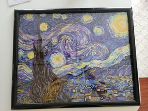 A framed diamond painting of Van Gogh's Starry Night painting with swirling night sky and village below.