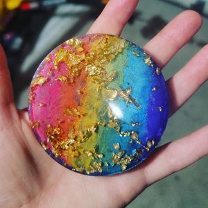 Colorful resin art piece featuring rainbow colors and gold foil on a circular surface.