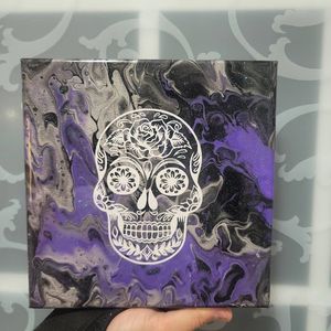A white sugar skull design on canvas with purple and black swirled background.