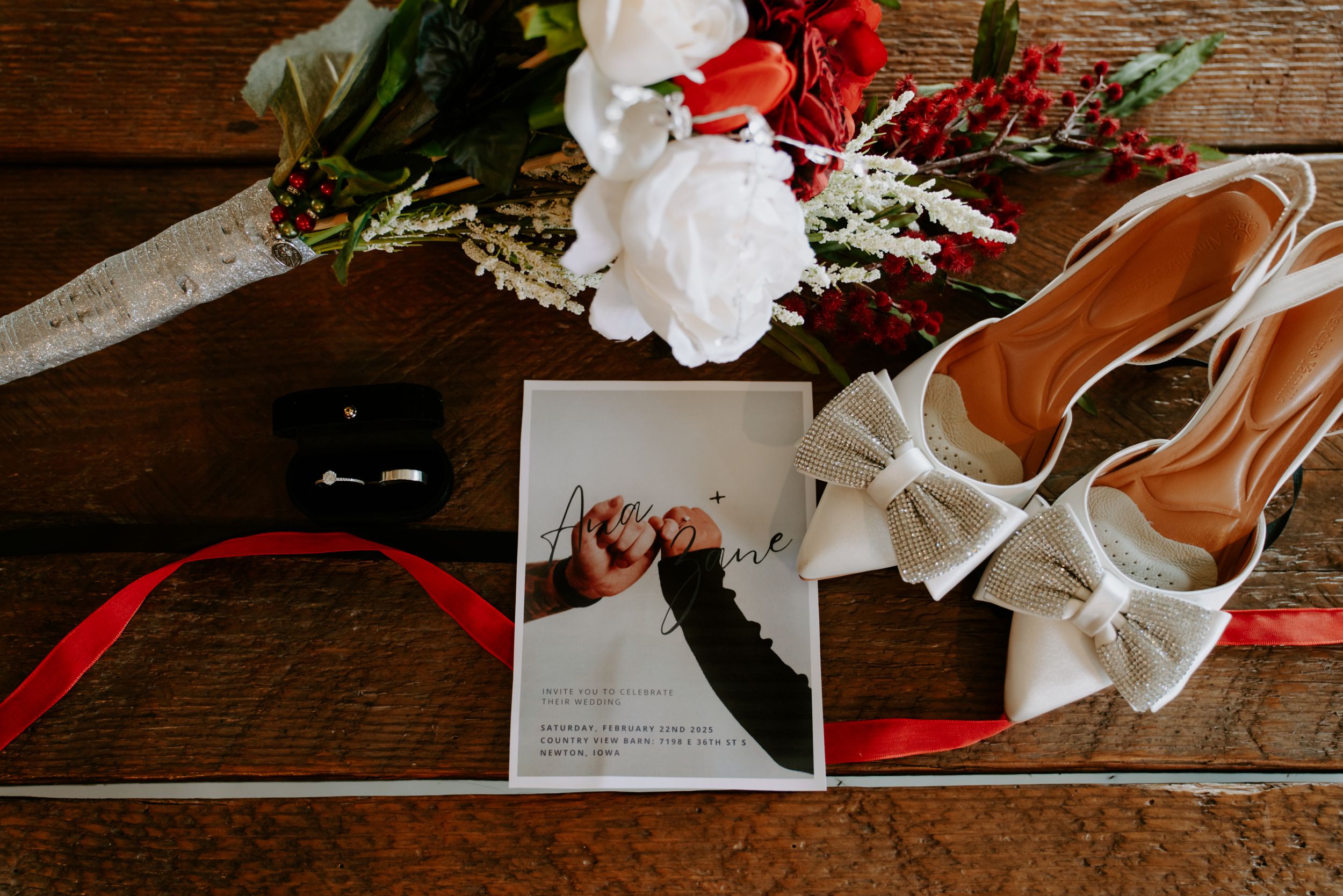 Wedding details including flowers, shoes, and accessories arranged on a dark wooden surface.