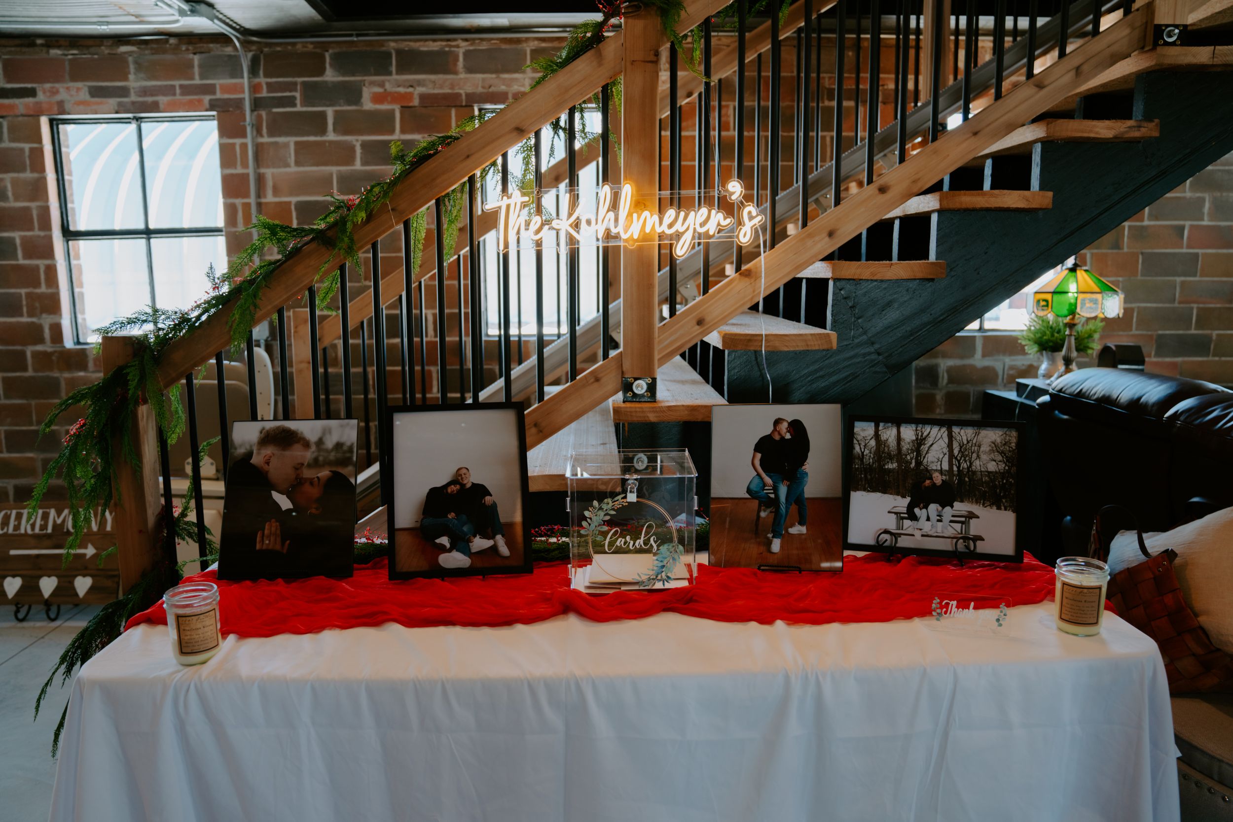 A long reception table setup with red accents and decorations along a staircase.