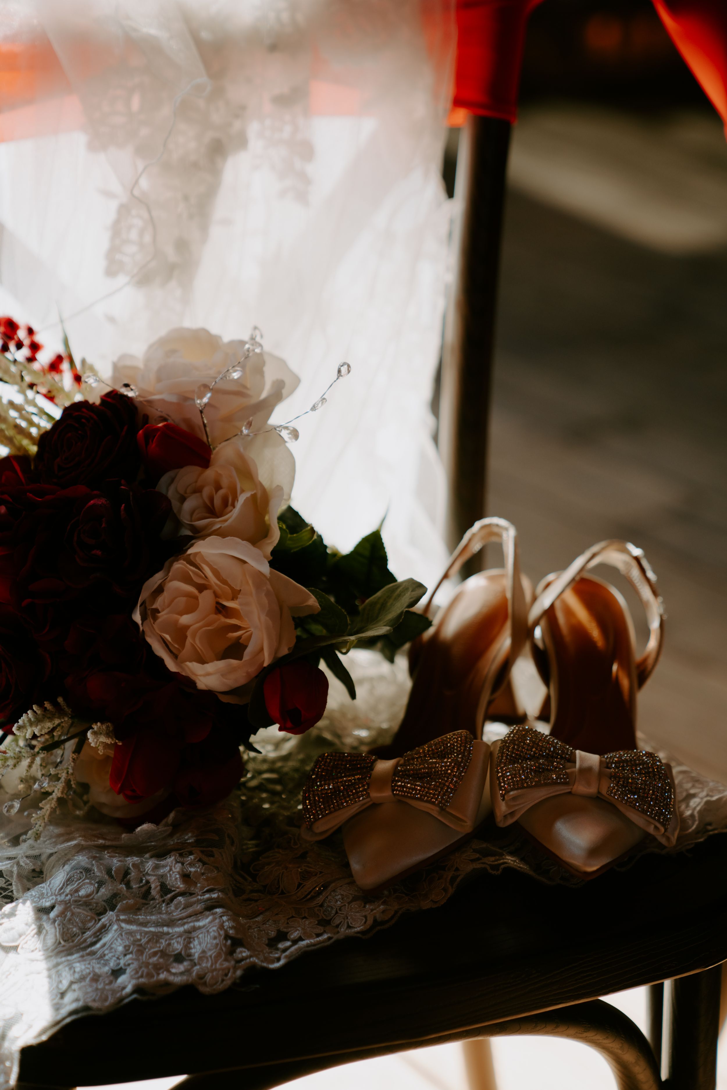 Delicate floral wedding decorations with pink roses and white fabric arranged on a dark surface.