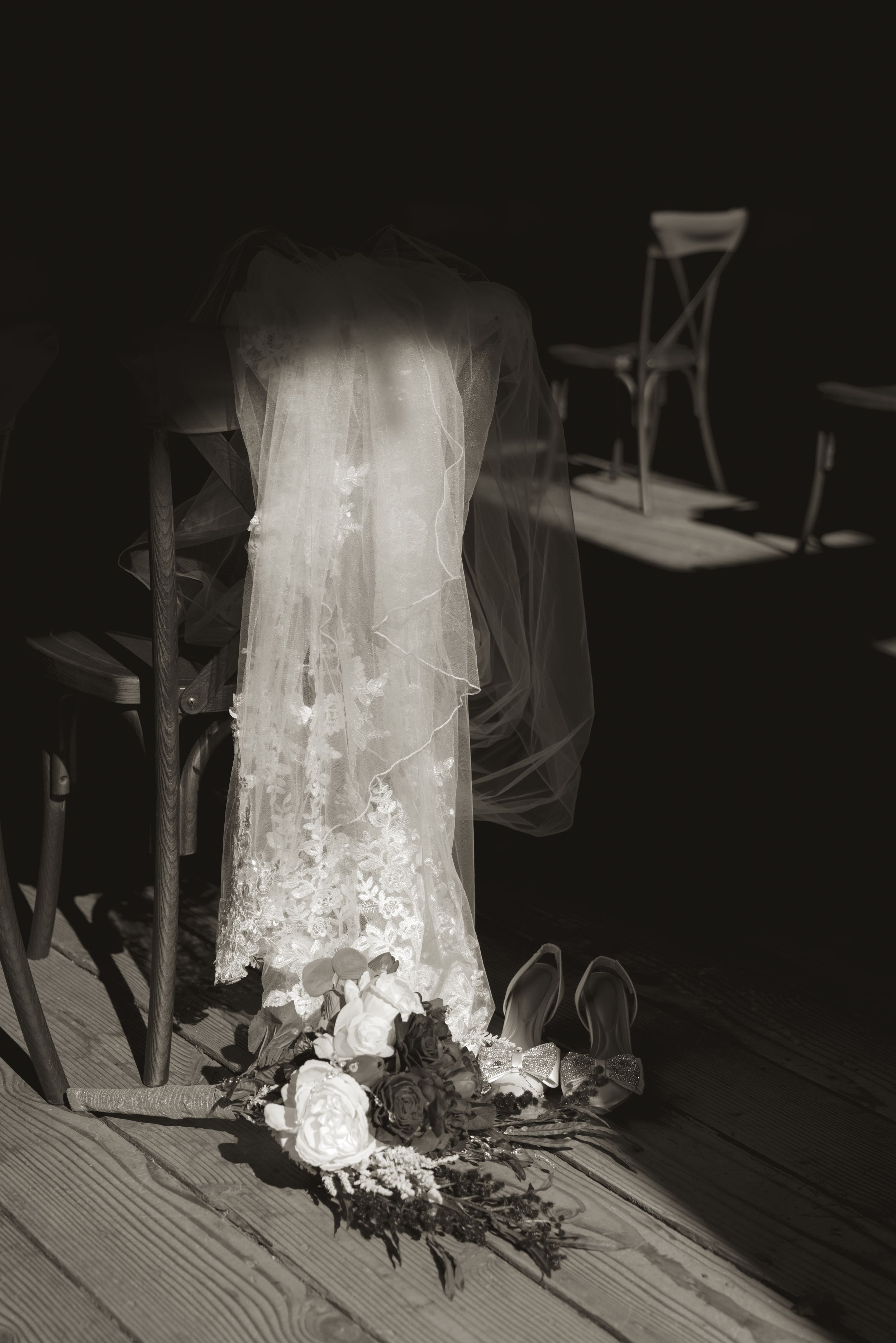 Ethereal white wedding dress train illuminated against dark wooden floorboards.