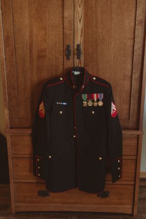 Military dress uniform with medals and decorations displayed on wooden paneled wall.