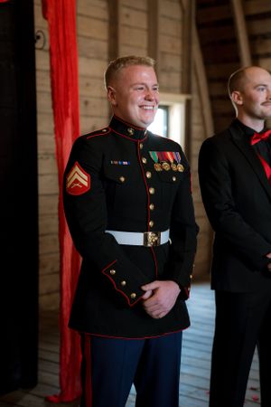 Marines in dress uniforms stand in formation inside a wooden building.