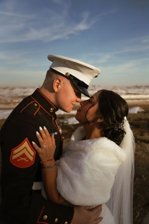 Military wedding couple embracing against a desert landscape with dramatic sky.