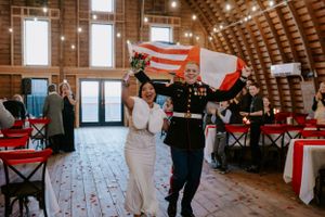 Wedding reception venue with rustic wooden beams and red chair decorations.