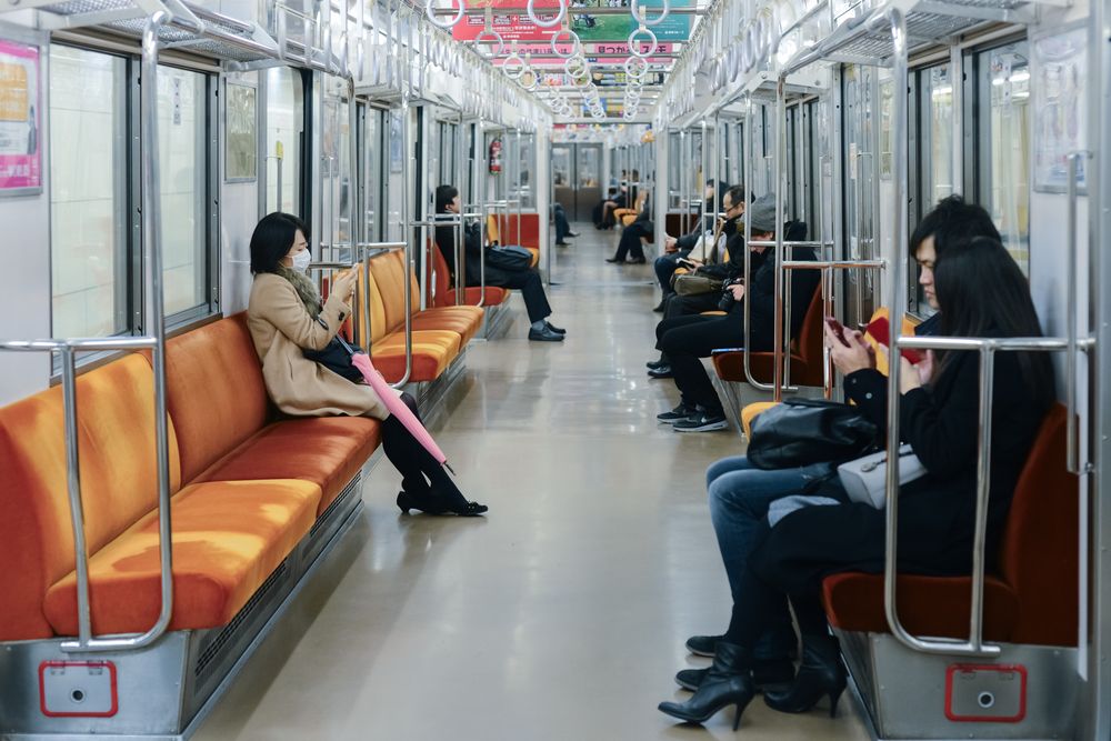 Empty subway car interior with orange seats and metal poles in Tokyo's metro system.