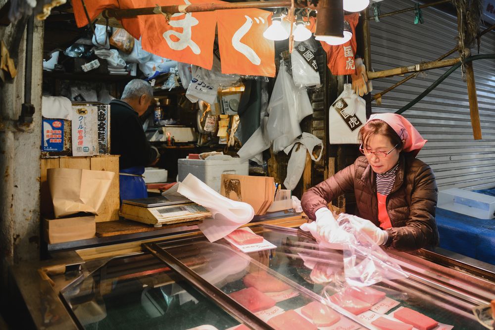 Fish market vendor displaying fresh seafood under red lighting at night.