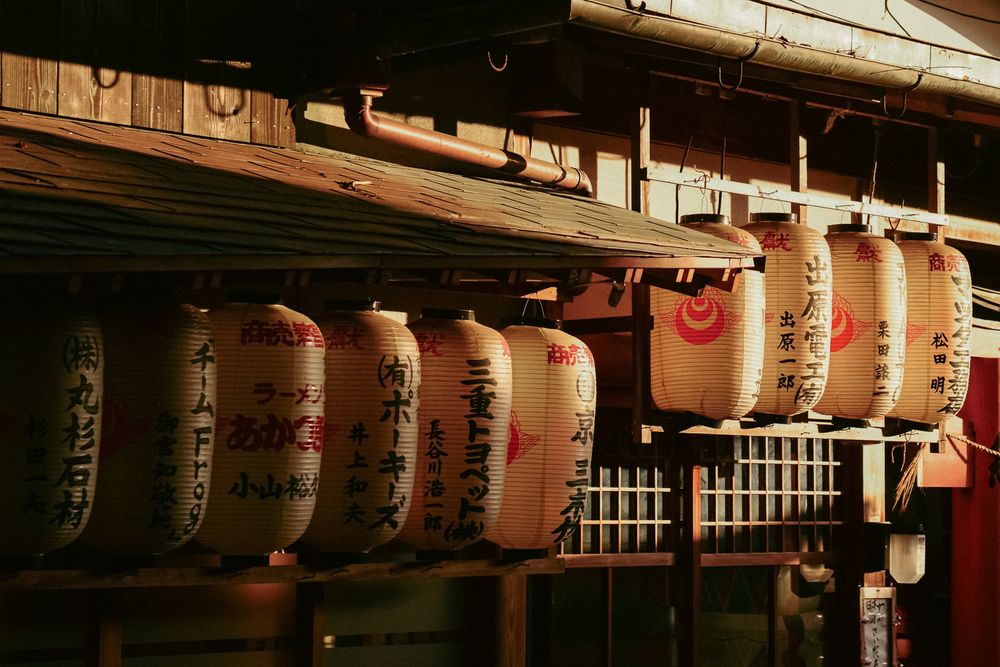 Row of traditional Japanese paper lanterns illuminated at night outside a temple or shrine.