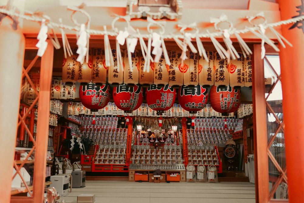 Long row of vibrant red torii gates with white paper lanterns at a Japanese shrine.