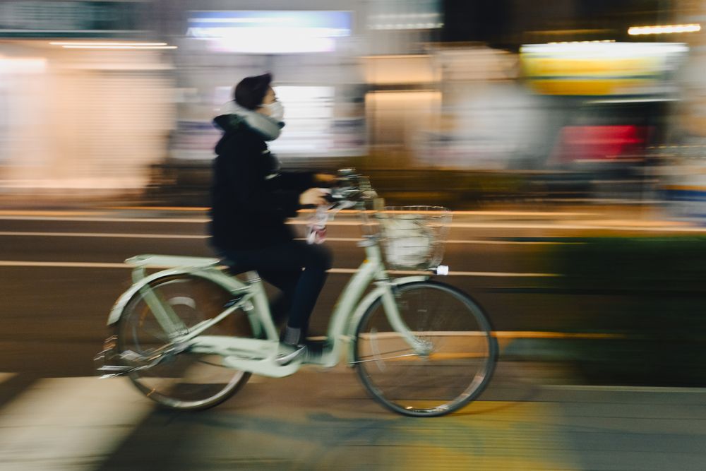 People cycling on an illuminated street with dramatic motion blur effects.
