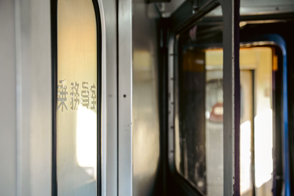 Interior corridor of a modern train with sunlight casting shadows through windows.