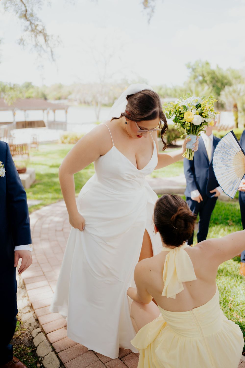 In a sunny outdoor setting, two people share a special moment on brick steps, with one wearing a white wedding gown.