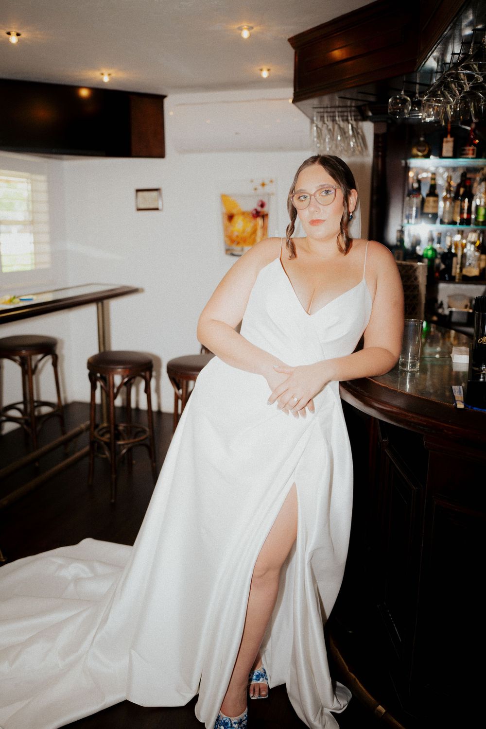 Elegant figure in a flowing white gown with high slit holding a cocktail at enzos on the lake