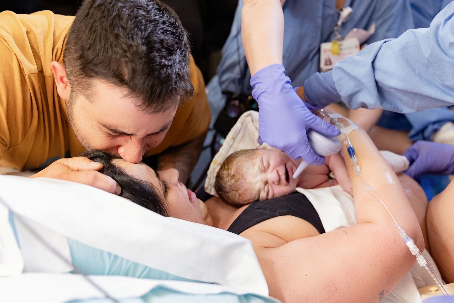 Medical team helps patient during intense moment of childbirth in hospital delivery room.